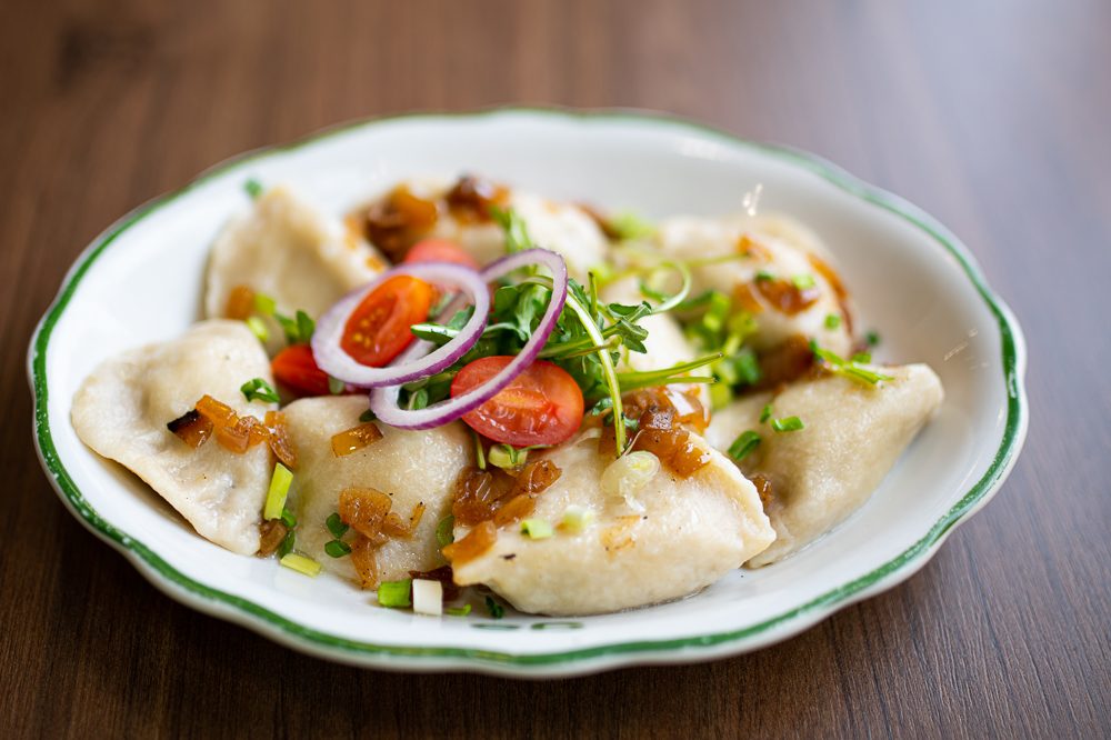 Pierogi z okrasą i szczypiorkiem na talerzu Olsztyniaka